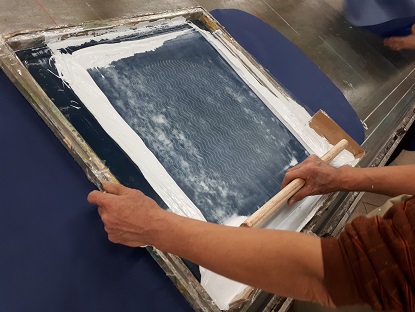 Screen printing on bags, done on the piece of fabric before the stitching. The ink moves through the mesh to the fabric.